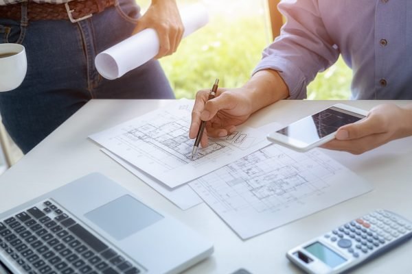 Engineer or architect teamwork working on construction project with building model and blueprint in office. Construction concept.